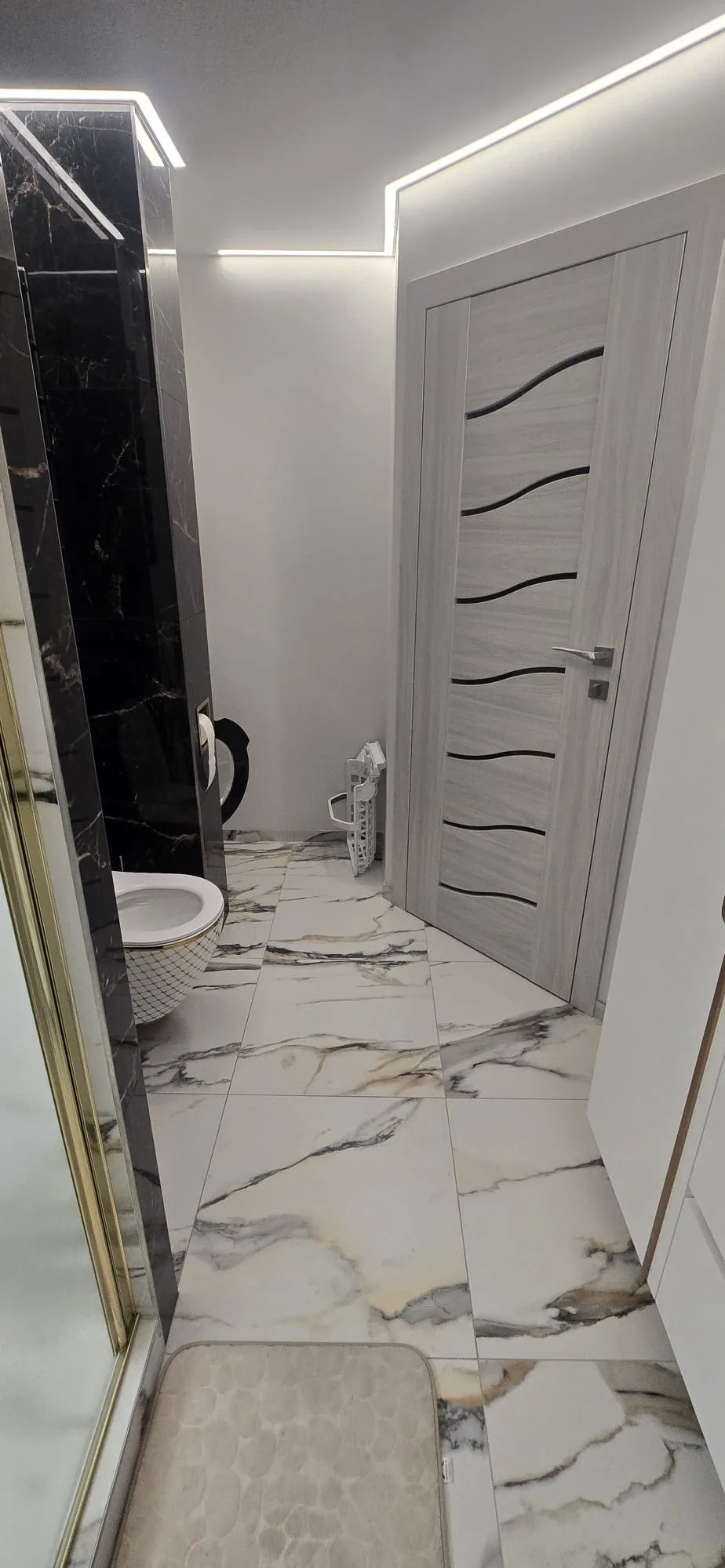 Marble-effect tiled bathroom floor and grey glazed door after a full bathroom refit in West Norfolk