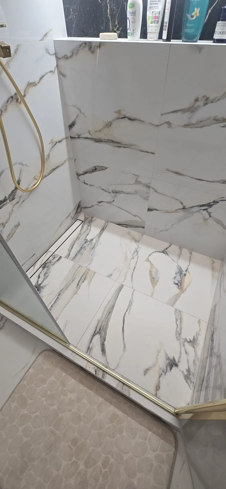 Tanked wet room floor with marble-effect tiles and a linear shower drain installed in Norfolk